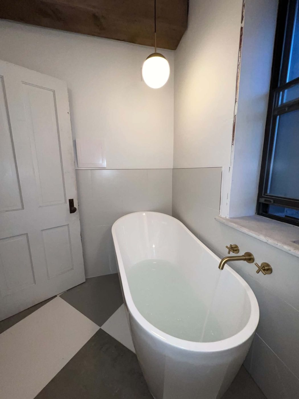 Freestanding bathtub filling with water in a finished bathroom