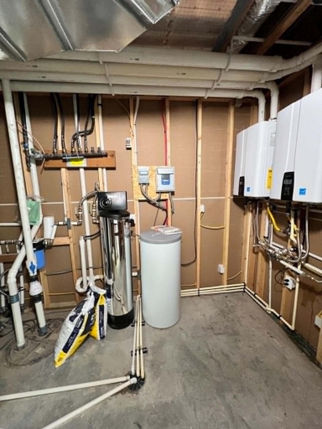 Utility room with water softener, filtration system, and tankless water heaters mounted on the wall